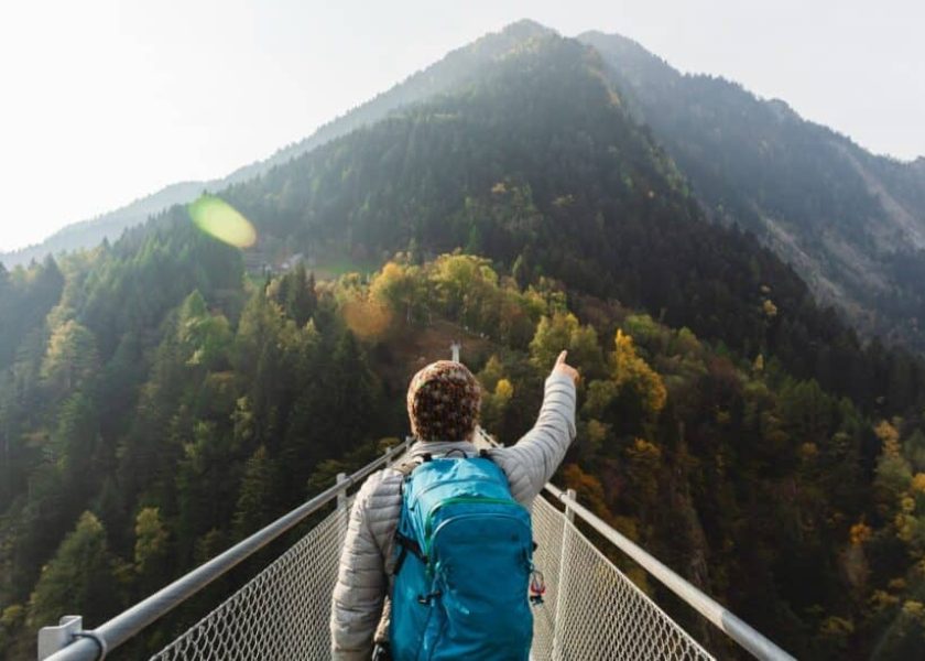 solo-hiker-pointing-with-hand-on-suspension-bridge-picture-id1055872516-1044×587