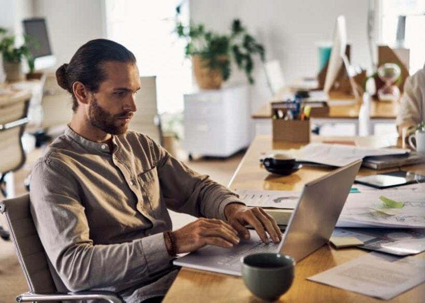 young-caucasian-businessman-using-a-laptop-sitting-at-a-desk-at-work-picture-id1394396760-1-1044×587