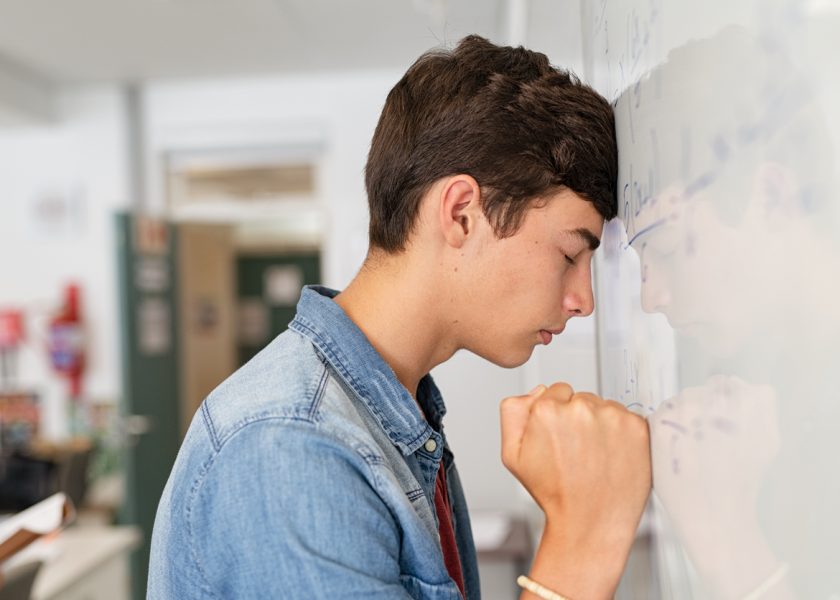 Stressed high school student having difficulty solving the equation at white board