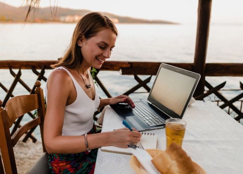 Young woman studying in a seaside restaurant in Greece